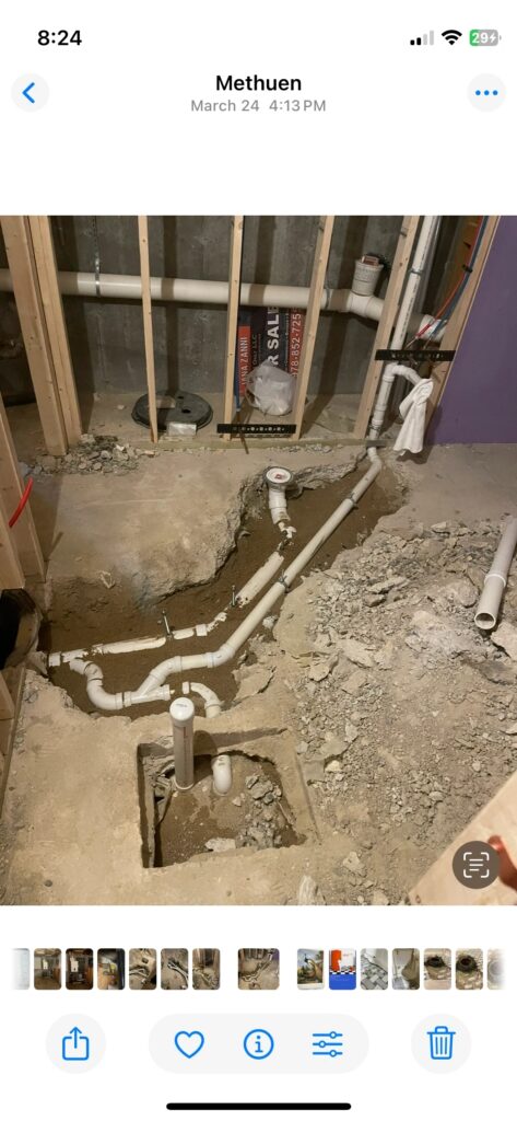 Basement plumbing installation with exposed pipes and concrete floor excavation.
