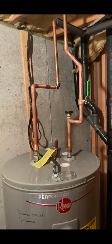 New Rheem water heater with copper piping installed in a basement.